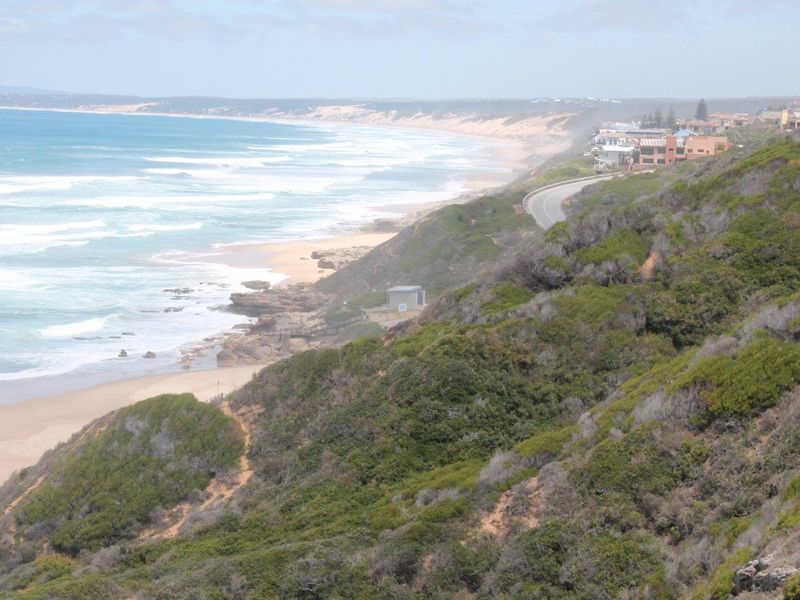 A scenic elevated view of the coastline, sandy beach, and ocean, showcasing the natural landscape and surrounding coastal environment.