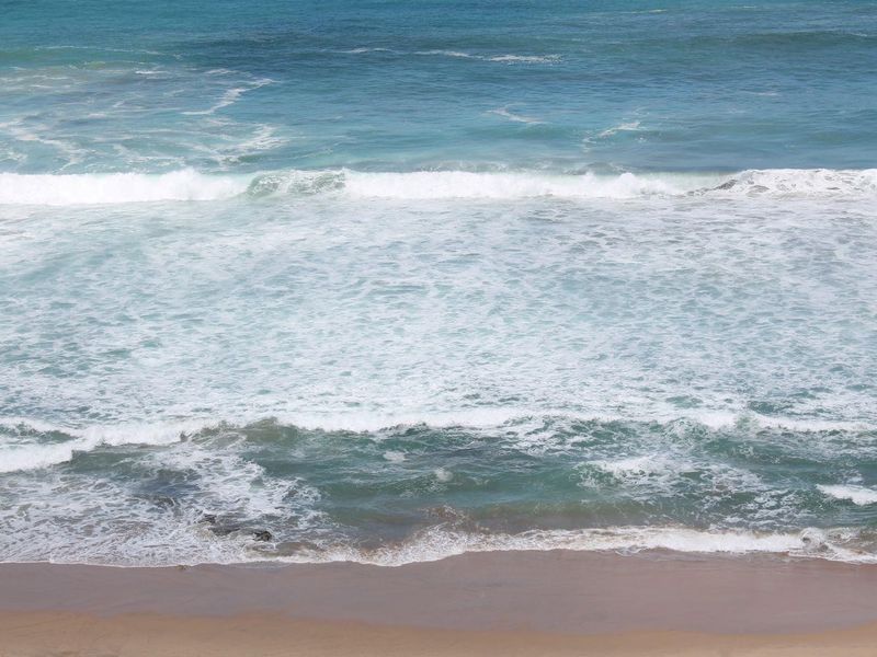 A scenic view of the ocean waves crashing onto the sandy beach.