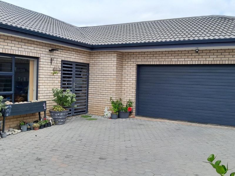 Front elevation of a brick house featuring a paved driveway, a secure garage door, and a modern tiled roof.