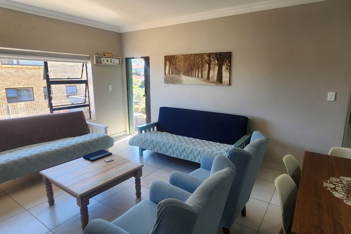 A bright living room featuring tiled flooring, cornicing, and direct access to an outdoor area through a glass door.