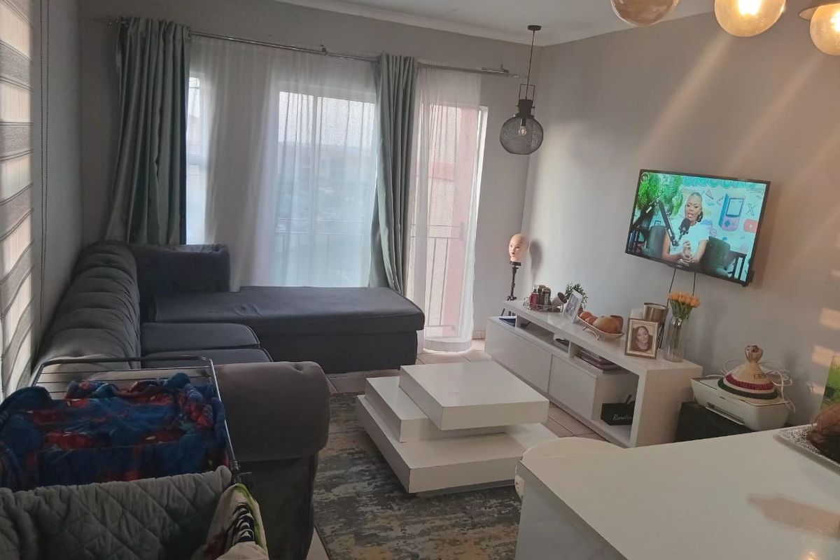 A comfortable living room featuring tiled flooring, modern pendant lighting, and a sliding glass door providing access to an outdoor balcony area.