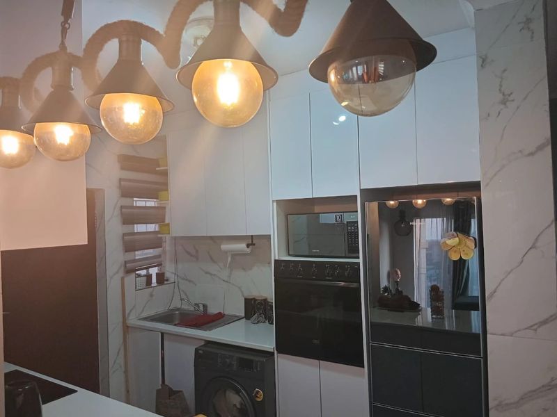 Modern kitchen featuring white high-gloss cabinetry, marble-look wall tiles, built-in oven and microwave, and integrated laundry facilities.