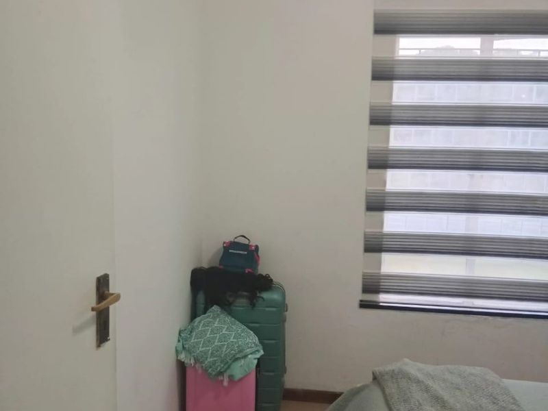 A bedroom featuring neutral walls, carpeted flooring, and modern zebra blinds, showing visible signs of ceiling water damage.