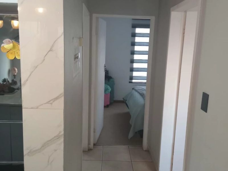 A functional hallway featuring tiled flooring and marble-look wall accents, providing access to adjacent rooms within the apartment.