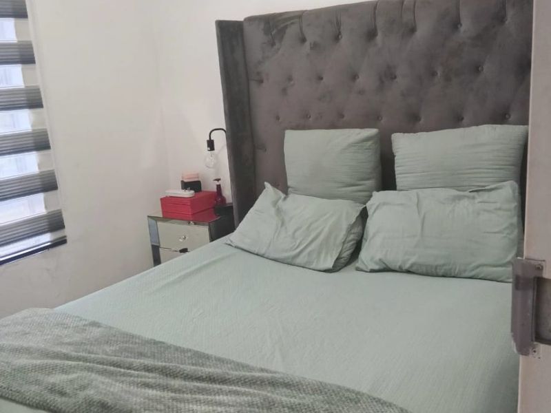 A bedroom featuring neutral walls and modern zebra blinds, showing a visible water stain on the ceiling.