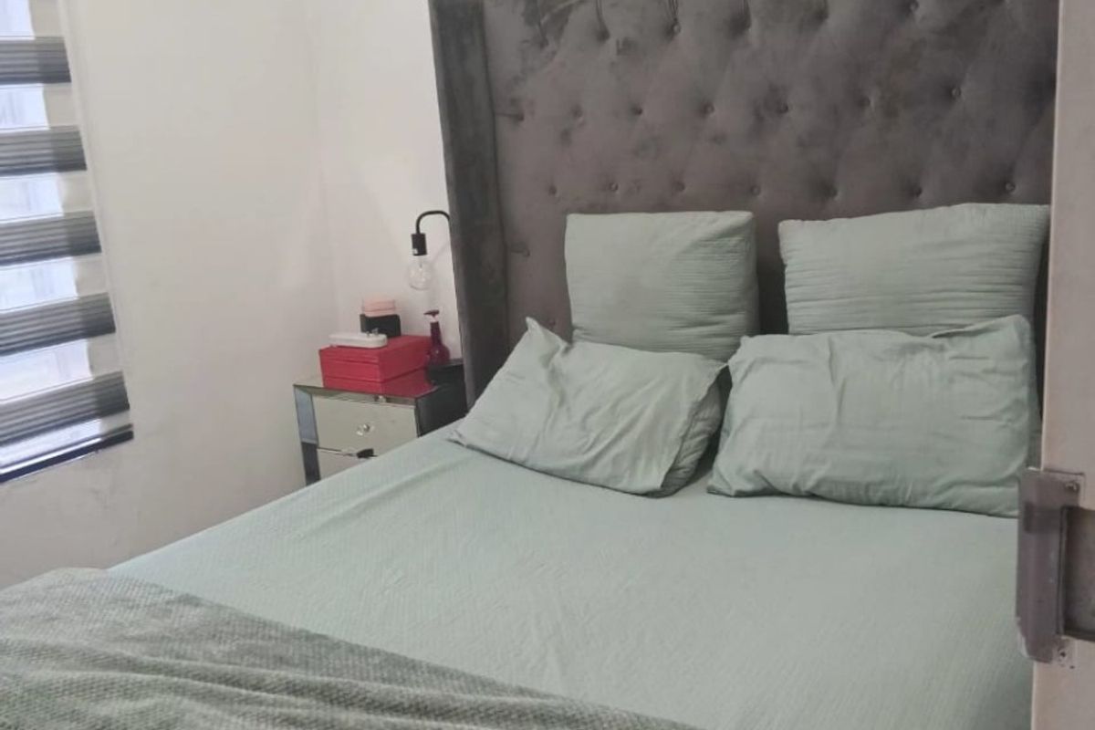 A bedroom featuring neutral walls and modern zebra blinds, showing a visible water stain on the ceiling.