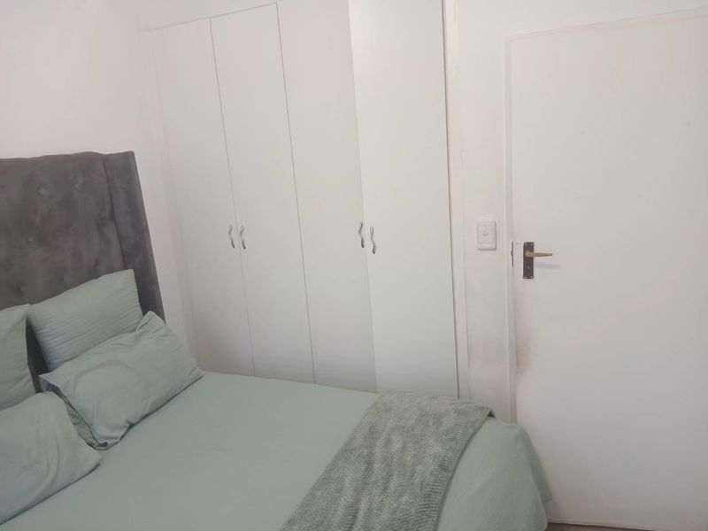 A bedroom featuring built-in white cupboards and a standard internal door, providing functional storage space.