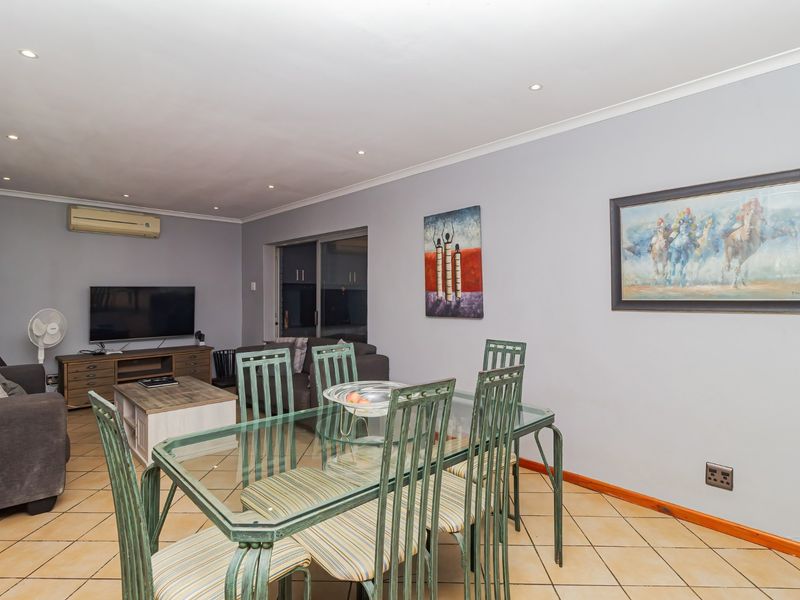 Open-plan living and dining area featuring ceramic tiled flooring, recessed lighting, and a wall-mounted split-system air conditioner.