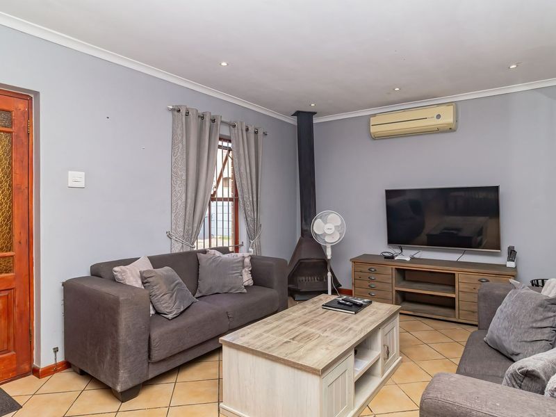 A comfortable living room featuring tiled flooring, a freestanding fireplace, and a wall-mounted air conditioning unit.