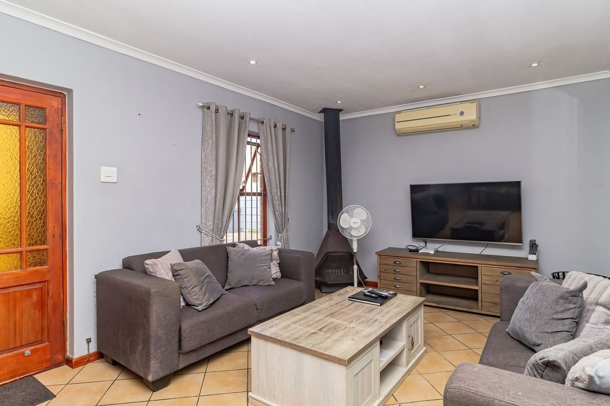 A comfortable living room featuring tiled flooring, a freestanding fireplace, and a wall-mounted air conditioning unit.