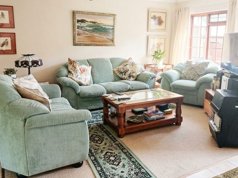A comfortable living room featuring neutral wall tones, carpeted flooring, and natural light from a window, providing a functional and inviting space.