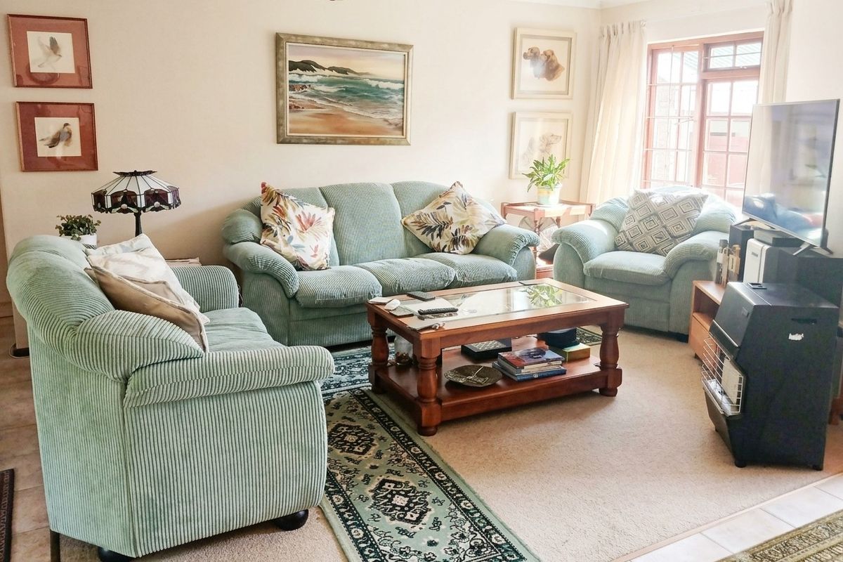 A comfortable living room featuring neutral wall tones, carpeted flooring, and natural light from a window, providing a functional and inviting space.
