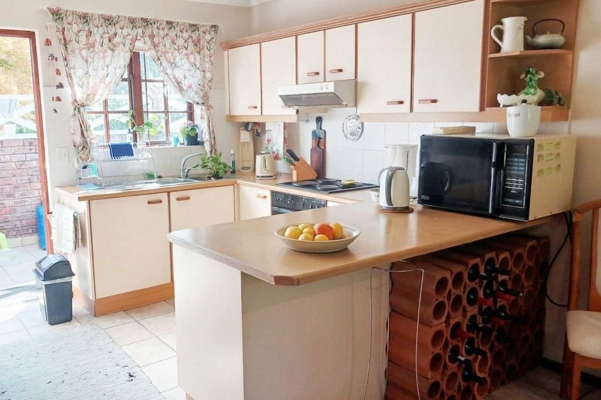 A functional kitchen featuring laminate countertops, built-in cabinetry, a hob, oven, and a unique integrated wine rack, offering a practical layout for daily use.