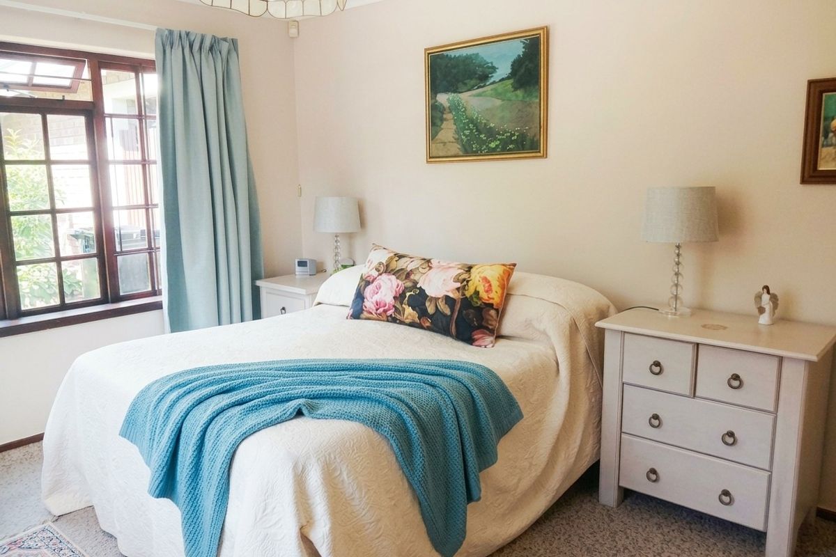 A well-maintained bedroom featuring carpeted flooring, coving, and a timber-framed window, offering a comfortable and functional living space.