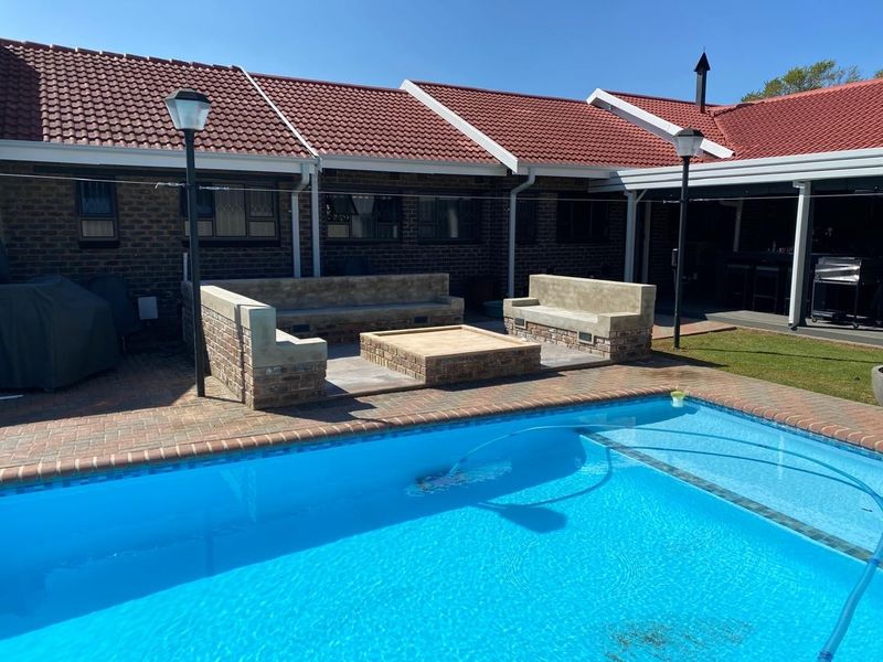 Outdoor entertainment area featuring a swimming pool, paved patio, and a built-in brick fire pit with integrated seating.