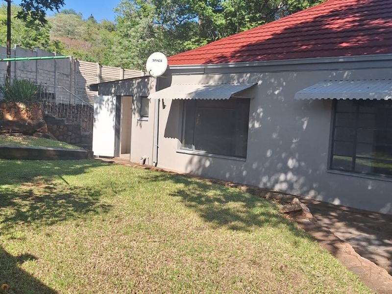 Rear exterior view of the house featuring a tiled roof, metal window awnings, and a private garden area with boundary walling.