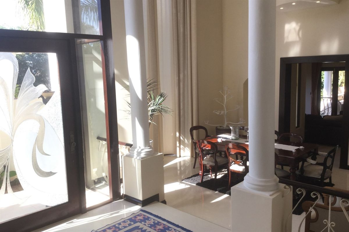 Spacious living area featuring high ceilings, decorative architectural columns, and large glass doors providing ample natural light.