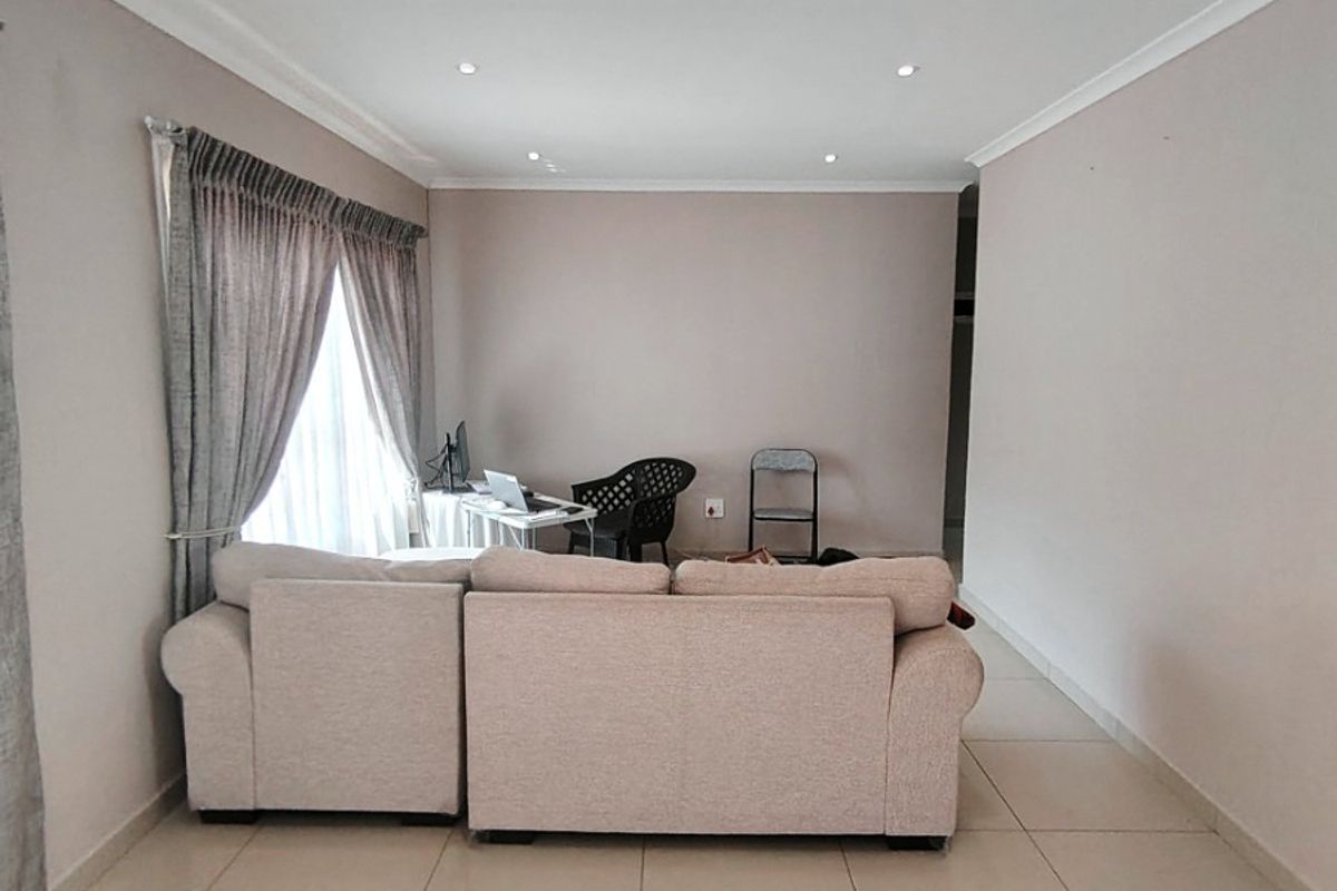 A spacious living room featuring neutral tiled flooring, recessed downlighting, and coved cornicing, providing a clean and versatile foundation for interior design.