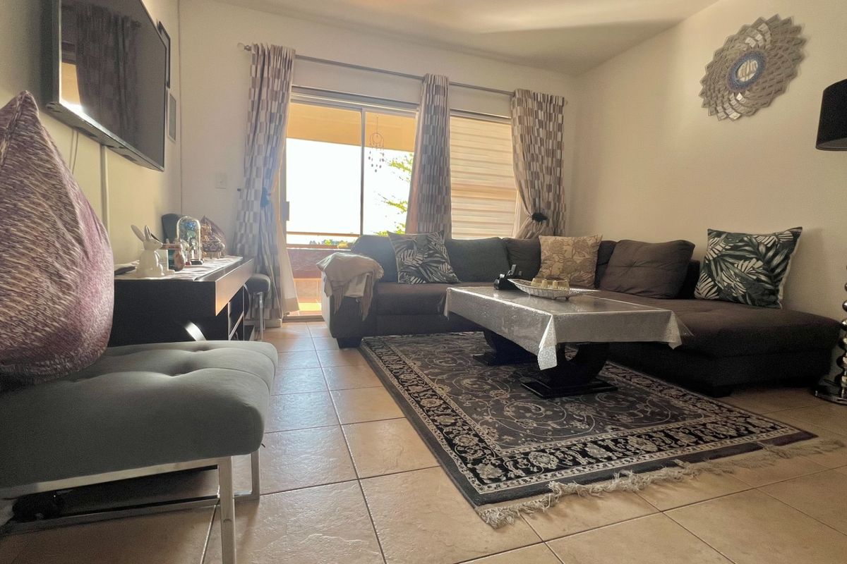 A comfortable living room featuring tiled flooring and a large sliding glass door that provides access to an outdoor balcony area.