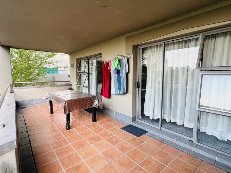 A covered balcony featuring tiled flooring, metal balustrades, and large sliding glass doors providing access to the interior living space.