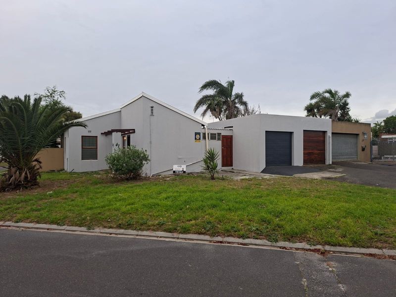 Front elevation of a townhouse featuring a double garage, paved driveway, and a timber entrance door with a small pergola.