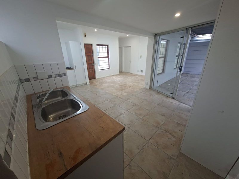 Open plan kitchen and living area featuring tiled flooring, a double bowl sink, and sliding glass doors leading to an outdoor patio space.
