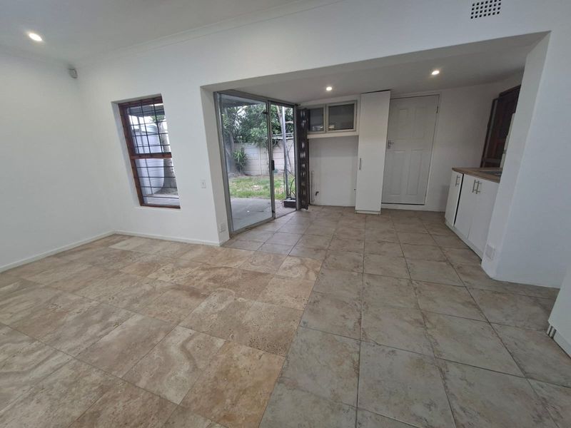 An open-plan living area featuring tiled flooring, built-in cabinetry, and a sliding glass door providing direct access to the rear garden.