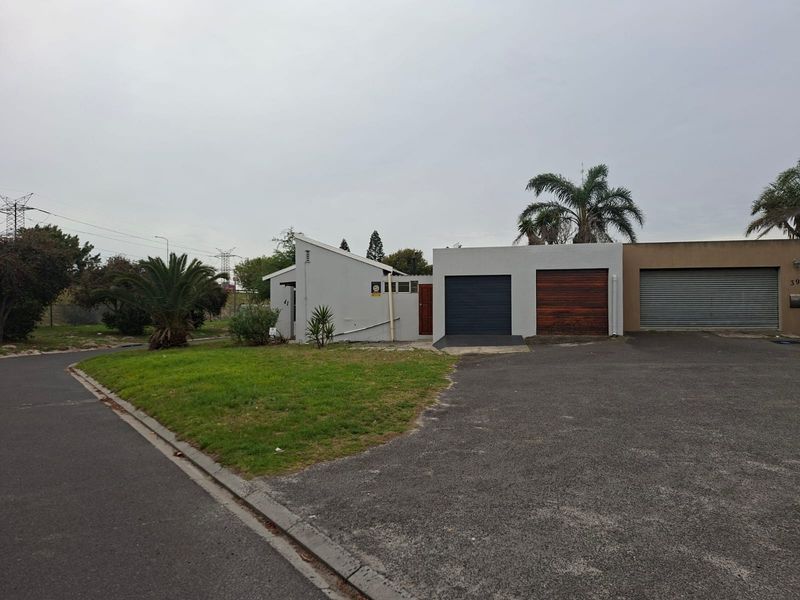 Front exterior view of a townhouse featuring a double garage with roller doors, an asphalt driveway, and a small front lawn area.