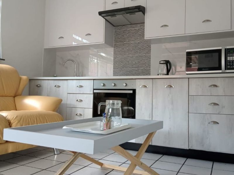 A functional kitchen featuring white cabinetry, a built-in oven with extractor fan, tiled backsplash, and tiled flooring.