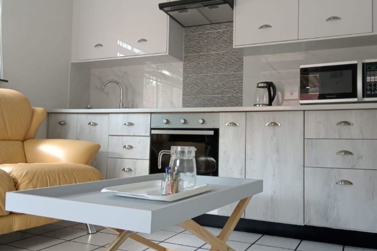 A functional kitchen featuring white cabinetry, a built-in oven with extractor fan, tiled backsplash, and tiled flooring.