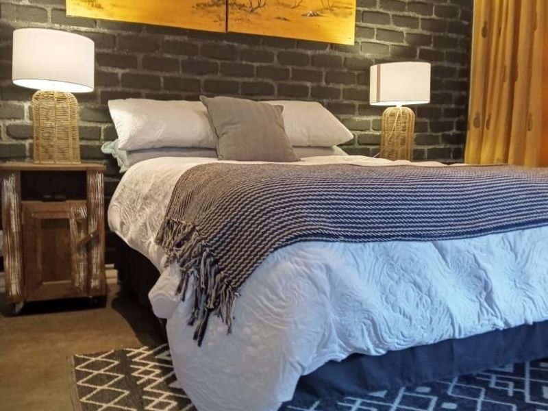 A cozy bedroom featuring a dark exposed brick feature wall and polished concrete flooring.