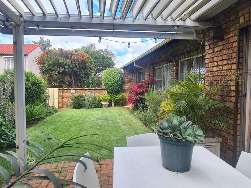 Covered patio area featuring a pergola, brick paving, and direct access to a well-maintained rear garden with established landscaping.
