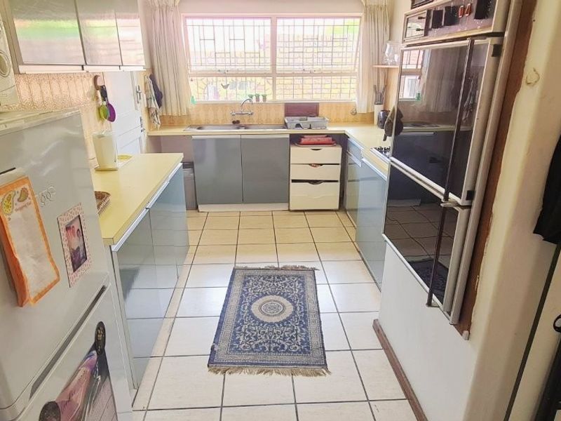 A functional galley-style kitchen featuring built-in cabinetry, a double wall oven, and tiled flooring, offering a practical layout with potential for modern updates.