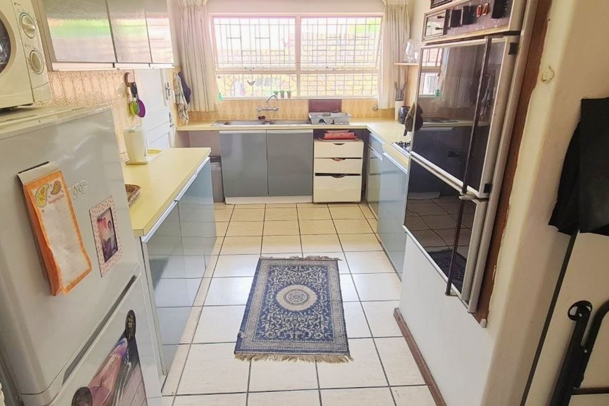 A functional galley-style kitchen featuring built-in cabinetry, a double wall oven, and tiled flooring, offering a practical layout with potential for modern updates.