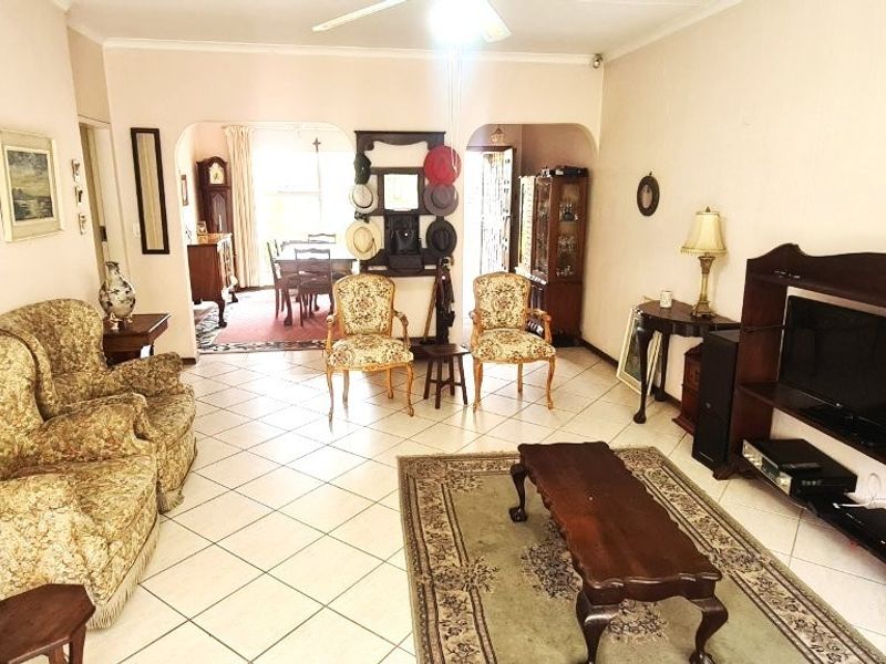 Spacious open-plan living and dining area featuring tiled flooring, a ceiling fan, and classic archway transitions between the living and dining spaces.
