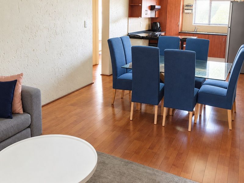 Open-plan living and dining area featuring laminate flooring, textured walls, and an integrated kitchen with built-in cabinetry.