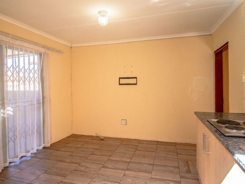 Open plan living and kitchen area featuring tiled flooring, built-in hob, and sliding door access to the exterior.