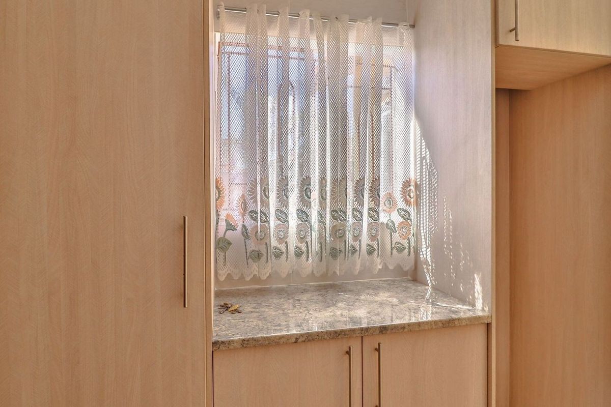 A functional kitchen area featuring light wood-look laminate cabinetry, granite countertops, and a tiled splashback, providing ample storage and workspace.