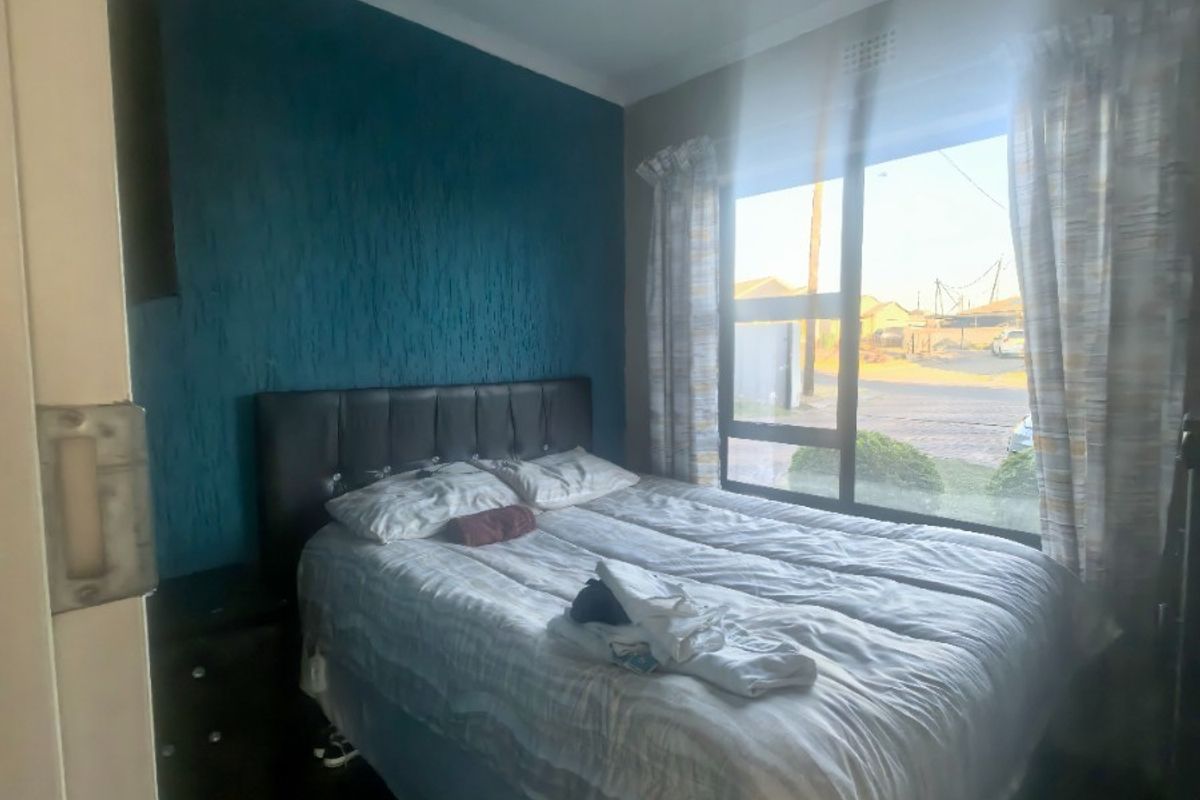 A bedroom featuring a large window and a textured blue accent wall, providing natural light and a distinct focal point.