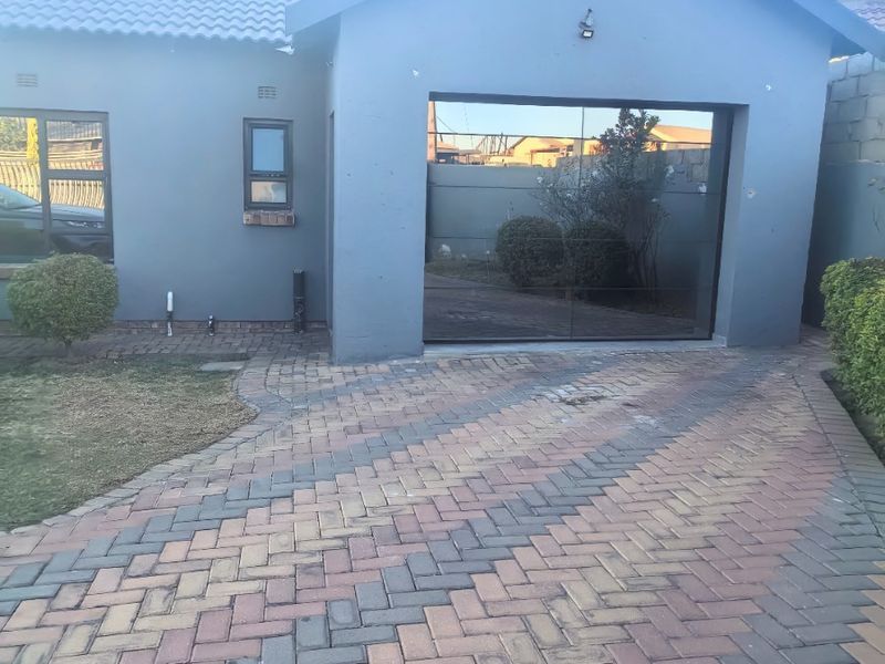 Front view of the property featuring a paved driveway, a single garage, and a modern grey facade with tiled roofing.