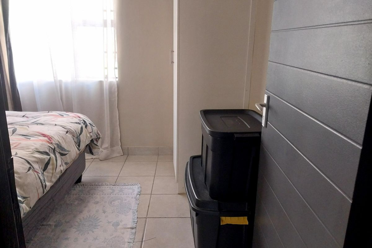 A bedroom featuring tiled flooring, a built-in cupboard, and a modern horizontal panel door, providing a functional and neutral living space.