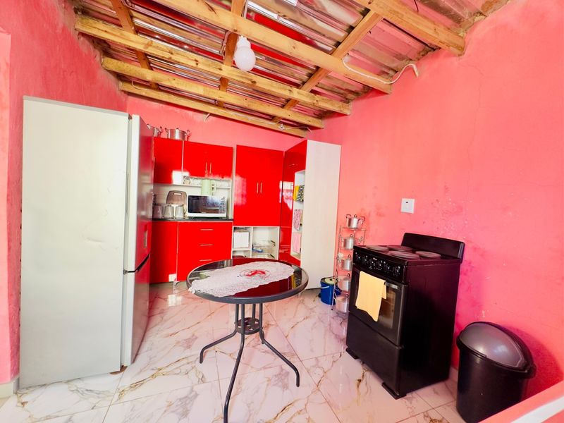 A kitchen area featuring red cabinetry, marble-look floor tiles, and an exposed timber roof structure.