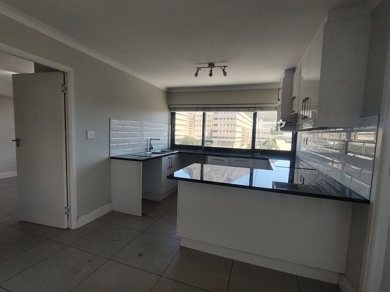 A functional kitchen featuring white cabinetry, dark granite countertops, and a subway tile backsplash, offering a clean and neutral space for culinary activities.