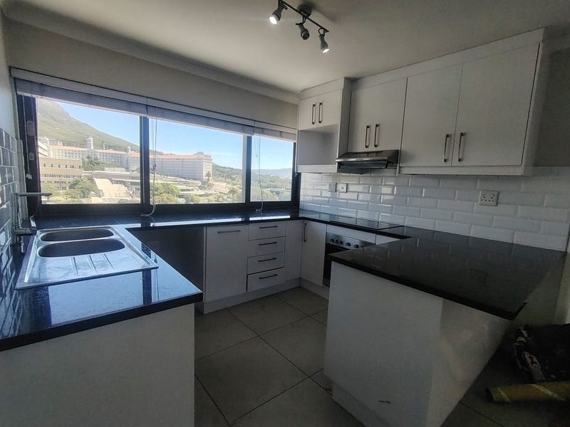 Modern kitchen featuring white cabinetry, granite countertops, subway tile backsplash, and integrated appliances, complemented by large windows with scenic views.