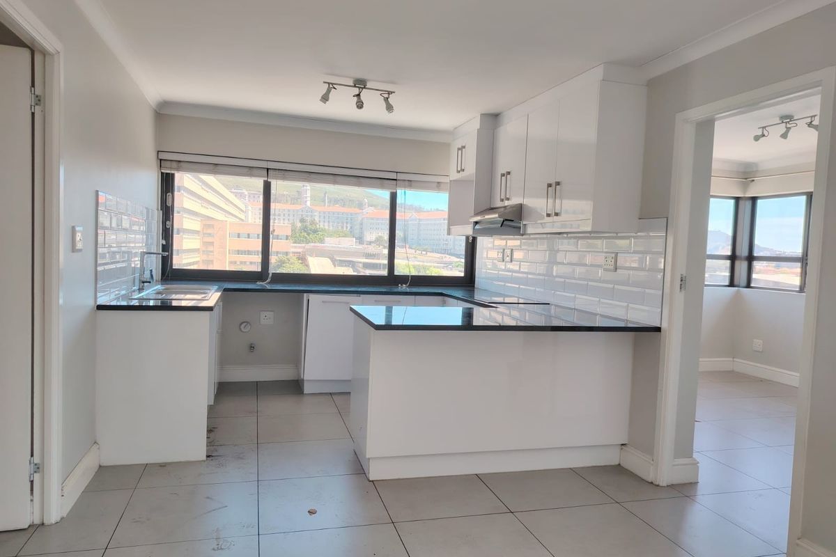 A clean, modern kitchen featuring white cabinetry, dark granite countertops, and a subway tile backsplash, offering a bright and functional workspace.