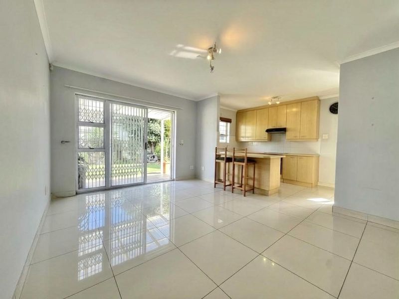 Open-plan living area featuring tiled floors, a modern kitchen with built-in cabinetry, and a sliding door providing access to the outdoor patio.