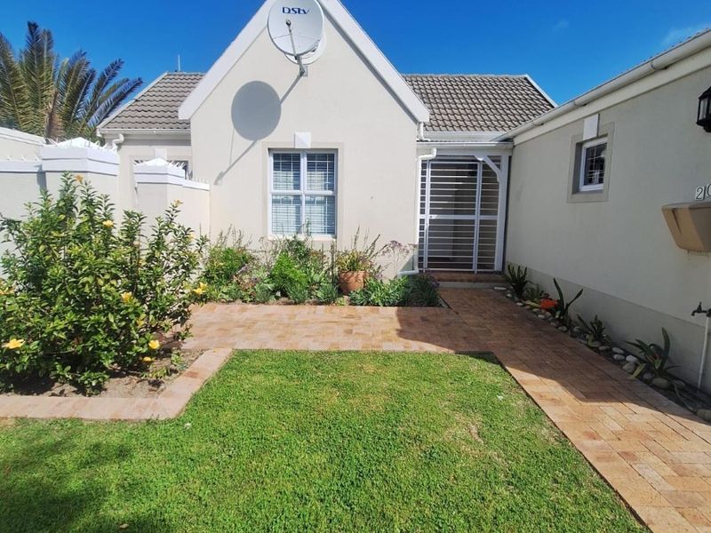 A well-maintained front entrance featuring a paved walkway, manicured lawn, and secure gated access to the home.