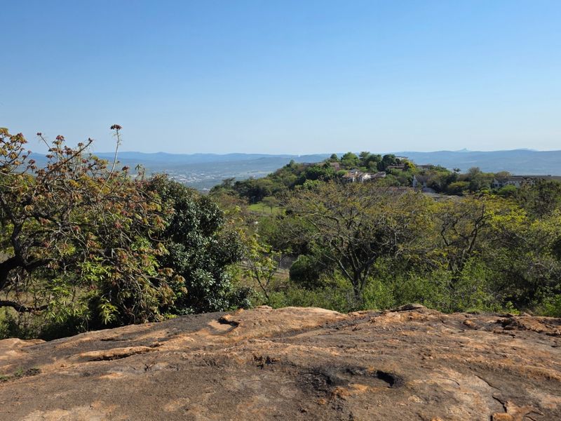 A scenic elevated view overlooking a lush landscape with rolling hills and distant residential areas.