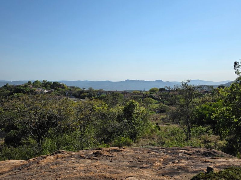 A scenic elevated view overlooking a lush landscape with distant hills and residential surroundings.