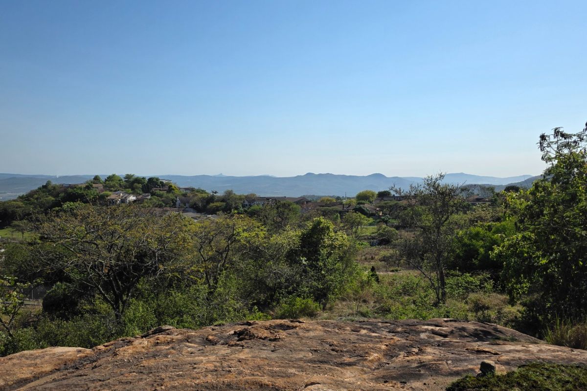 A scenic elevated view overlooking a lush landscape with distant hills and residential surroundings.